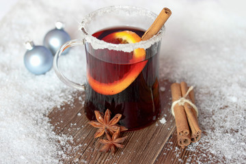 Ein Glas mit Glühwein, Orgenscheibe, Zimtstange auf altem Holz