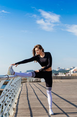 Sportive woman stretching near the sea.