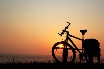Fototapeta na wymiar Silhouette of a bicycle against the orange sky at sunrise