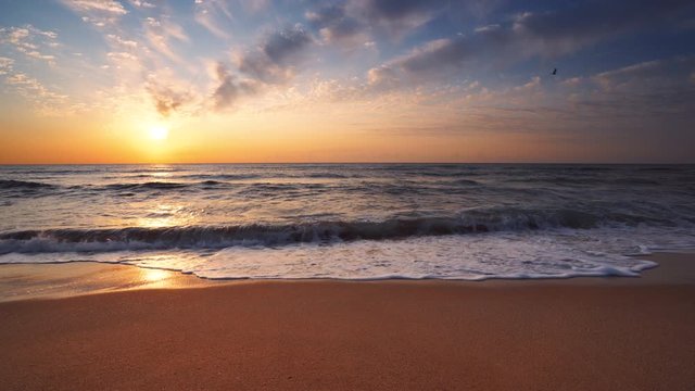 Sea sunrise, splashing waves and sandy beach