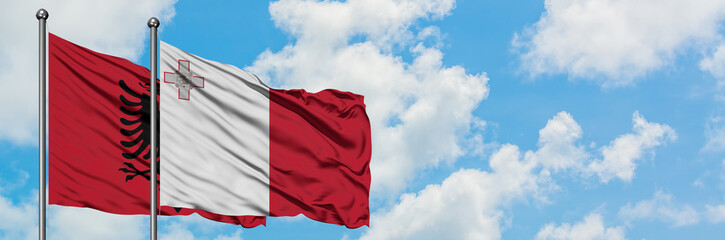 Albania and Malta flag waving in the wind against white cloudy blue sky together. Diplomacy concept, international relations.