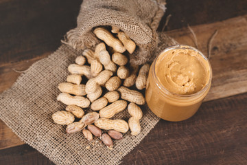 peanut butter spread and groundnuts on a wooden table. Concept of breakfast and peanut butter lover