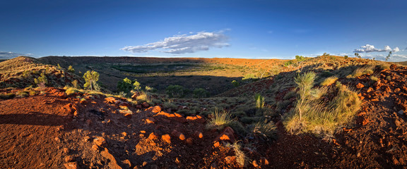 Large meteorite crater at the outback Australia – Wolf Creek crater with spinifex grass and boulders and blue sky as background in the morning sun