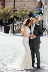 Fototapeta premium Happy couple in love on the background of buildings. Love story of couple in the city. Love story. Portrait of a beautiful young couple in love standing and kissing