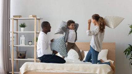 Happy multinational family pillow fight in bedroom