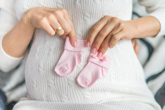 pregnant woman holds baby socks in her hands