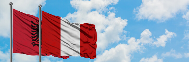 Albania and Peru flag waving in the wind against white cloudy blue sky together. Diplomacy concept, international relations.