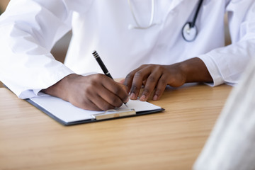 Close up of biracial doctor write prescription in medical card