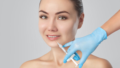 The doctor cosmetologist makes Lip augmentation procedure of a beautiful woman in a beauty...