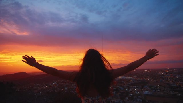 Girl with raised hands lowers them over epic view of Curacao 