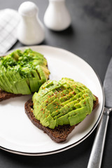 Rye bread toast with avocado on white plate. Healthy vegan vegetarian food