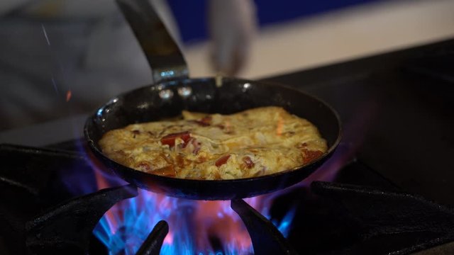 Chef fry omelette with eggs, sausage and vegetable on fire in frying pan . Cook frying eggs with vegetables in the kitche