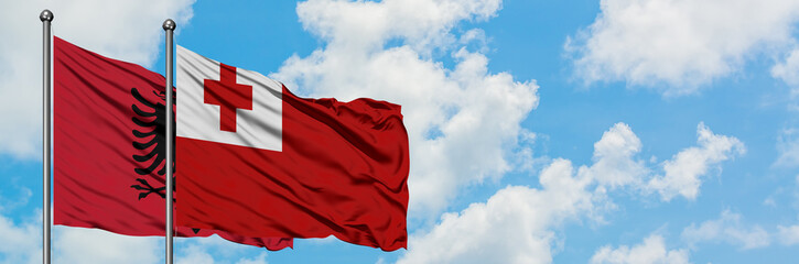 Albania and Tonga flag waving in the wind against white cloudy blue sky together. Diplomacy concept, international relations.