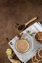 Masala tea in glass on wooden background in rustic style. Traditional Indian hot drink with milk, black tea and spices. Copy space, top view, close-up