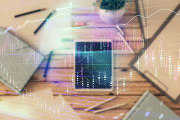 Double exposure of forex graph on digital tablet laying on table background. Concept of market analysis