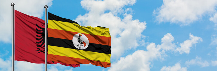 Albania and Uganda flag waving in the wind against white cloudy blue sky together. Diplomacy concept, international relations.