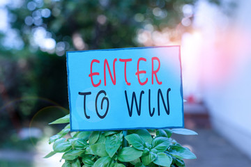 Text sign showing Enter To Win. Business photo text exchanging something value for prize or chance of winning Plain empty paper attached to a stick and placed in the green leafy plants