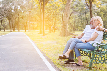 Retired couples aged, elderly, talking, sitting on a bench in the park.