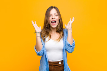 young pretty woman feeling shocked and excited, laughing, amazed and happy because of an unexpected...