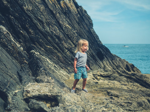 Little toddler playing on rocky beach in summer