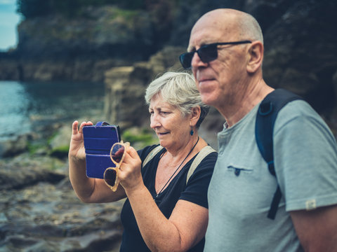 Senior couple taking photos with smartphone on the beach