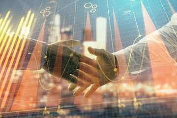 Double exposure of financial chart on cityscape background with two businessmen handshake. Concept of financial analysis and investment opportunities