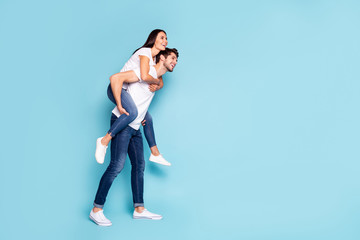 Full length body size profile side view of nice attractive lovely cheerful people piggybacking having fun free time isolated on bright vivid shine vibrant blue turquoise background