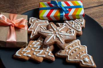Colorful gift boxes cookies dark black dish on a wooden dark background. The concept of preparing for the holidays New Year and Christmas.