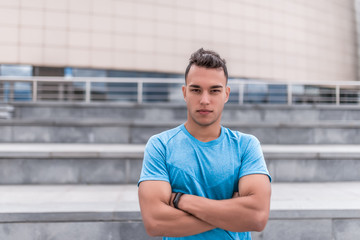 Male athlete posing confidently looking, coach summer day city, building background. Active youth lifestyle, fitness workout nature. Free space for text strength and motivation.