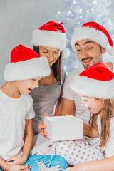 happy family mother father and children on Christmas morning in pajamas open gifts