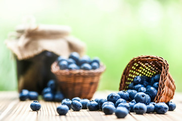 Blueberries in wicker basket and blueberry jam or marmalade.on old table with back light.