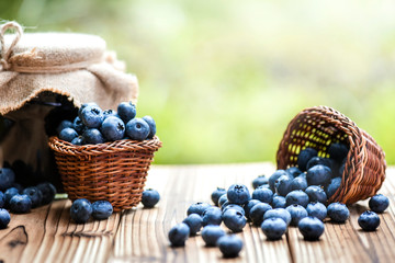 Blueberries in wicker basket and blueberry jam or marmalade.on old table with back light.