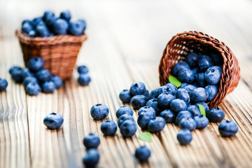 Blueberries on wooden rustic table. Wicker basket full of blueberry in background.
