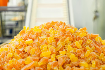 ready-made gumdrops lies on a tray in a pastry shop against a blurred interior with a conveyor belt