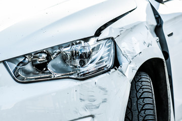 Car crash or accident. Front fender and light damage and scratchs on bumper. Broken vehicle detail or close up.