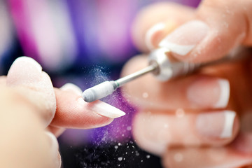 Nail manicure in woman beauty salon. Electric nails file in action, finger close up or detail with...