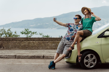 Travelers couple taking selfie with smart phone. Young man and woman taking self portrait while...