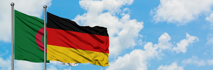 Algeria and Germany flag waving in the wind against white cloudy blue sky together. Diplomacy concept, international relations.