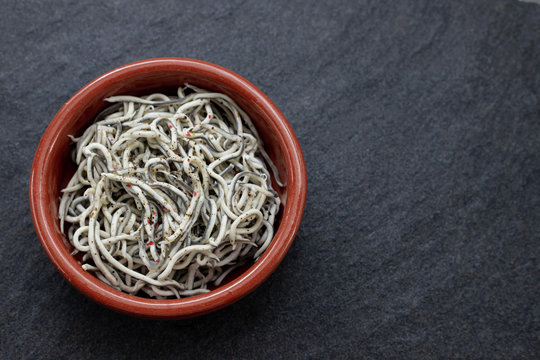 Traditional Spanish food. Gulas with oil in ceramic dish.