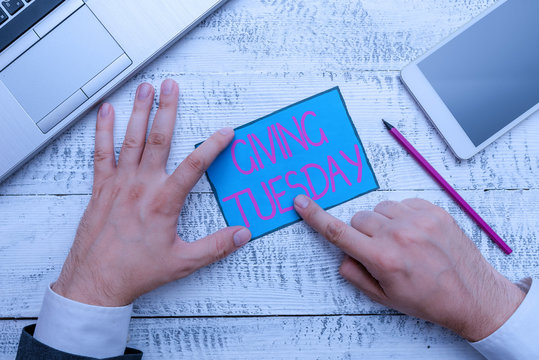 Text sign showing Giving Tuesday. Business photo text international day of charitable giving Hashtag activism Hand hold note paper near writing equipment and modern smartphone device
