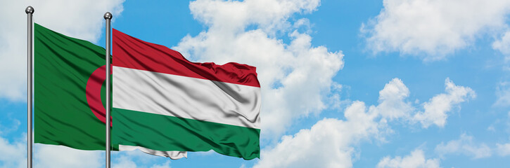 Algeria and Hungary flag waving in the wind against white cloudy blue sky together. Diplomacy concept, international relations.