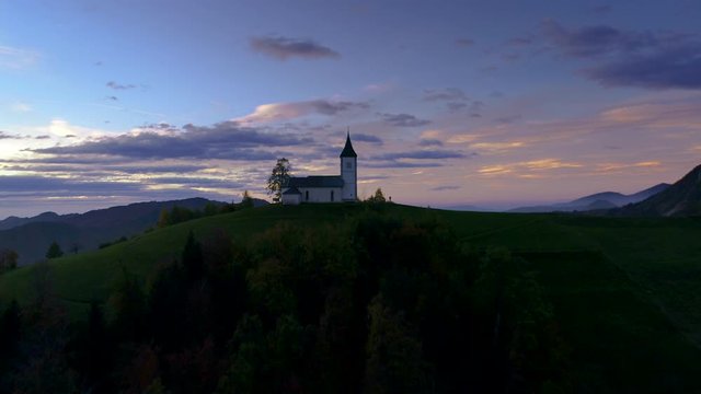 Aerial view of landscape of church of St. Primoz near Jamnik, Slovenia and Julian Alps at background