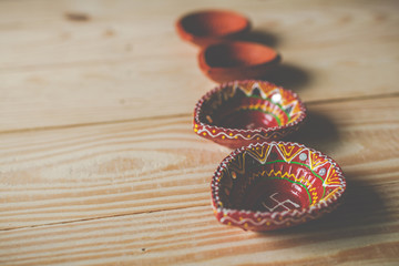 Happy Diwali - Clay Diya lamps lit during Dipavali, Hindu festival of lights celebration.oil lamp diya on wooden background