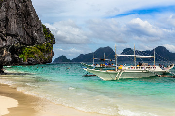 Tropical island landscape with bangca traditional phillipinians boats anchored at the shore, Palawan, Philippines