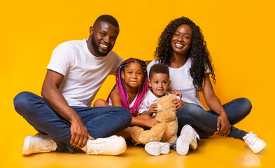 Afro family with daughter and son sitting together on floor