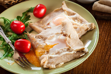 Crepes with ham, cheese and poached egg on a plate