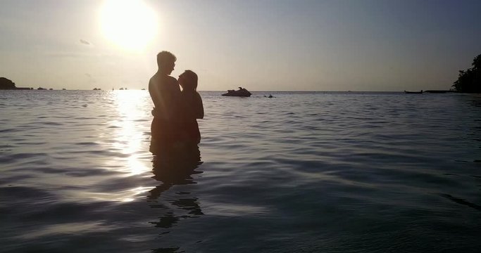 sumer love on sunset. Couple embracing, flirting and kissing on astonishing Thailand sunset. Backlight and silhouettes