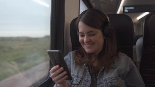 Happy girl smiling in train  with headphone and cellphone