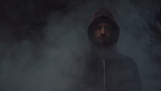 Portrait of computer hacker in hoodie. Obscured dark face. Data thief, internet fraud, darknet and cyber security .