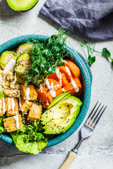 Buddha bowl with quinoa, tofu, avocado, sweet potato, brussels sprouts and tahini dressing, top view. Healthy vegan food concept.